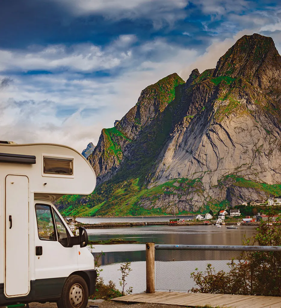 Camping-car stationné face à un fjord entouré de montagnes en Norvège