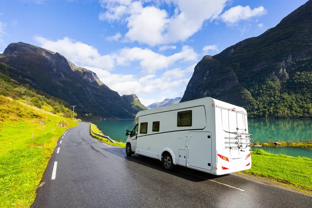 Camping-car circulant sur une route étroite au bord d’un fjord en Norvège
