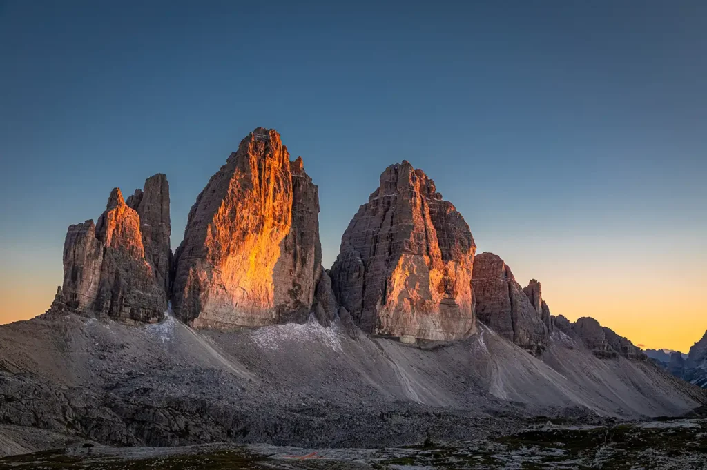 Les sommets des Tre Cime di Lavaredo dans les Dolomites italiennes, illuminés par la lumière dorée du soleil couchant